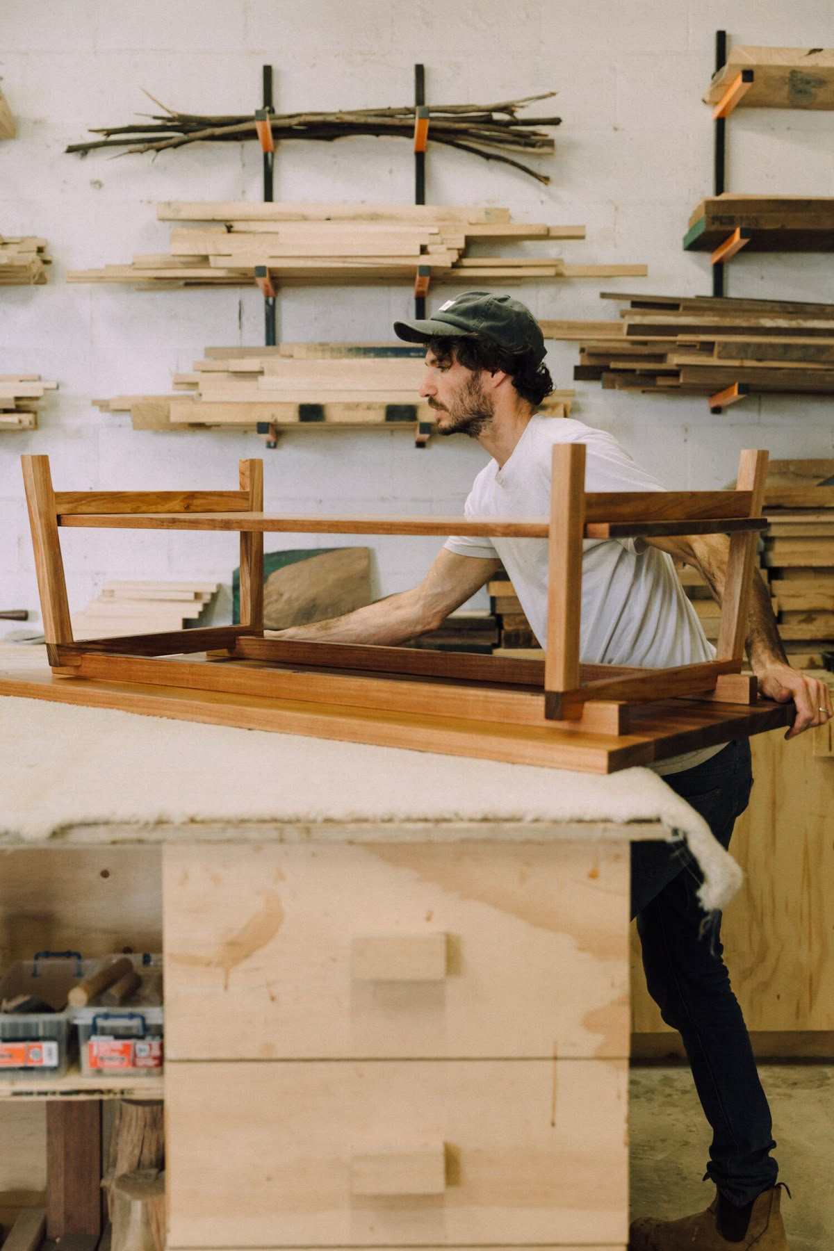 Un menuisier ajuste le piètement d'une table en noyer massif dans l'atelier