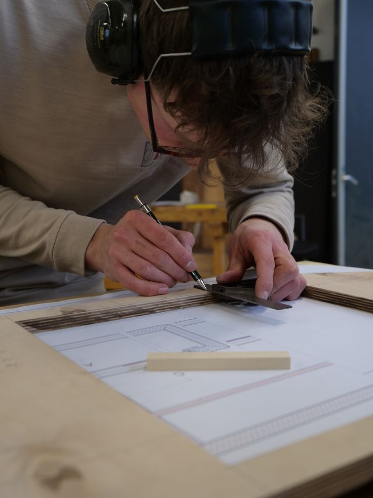 Un menuisier dessine un plan à l'établi