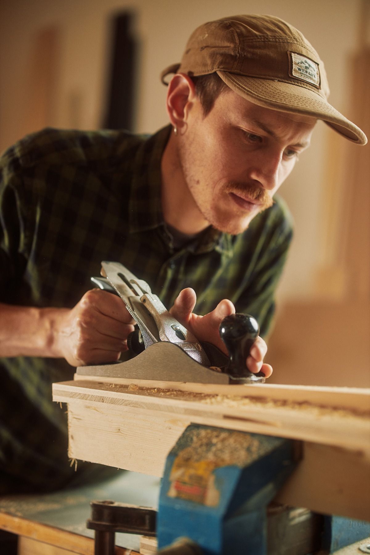 Un artisan rabote une pièce de bois serrée dans l'étau